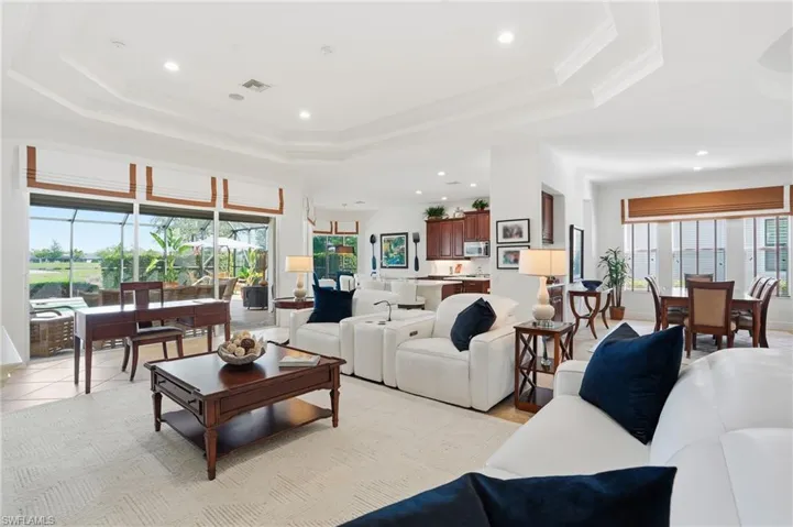 Living room featuring a tray ceiling, recessed lighting, and ornamental molding