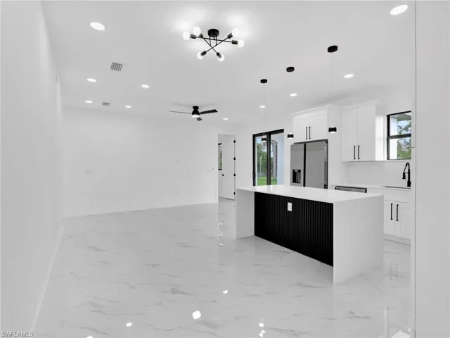 Kitchen with white cabinetry, a kitchen island, light marble finish floors, and recessed lighting