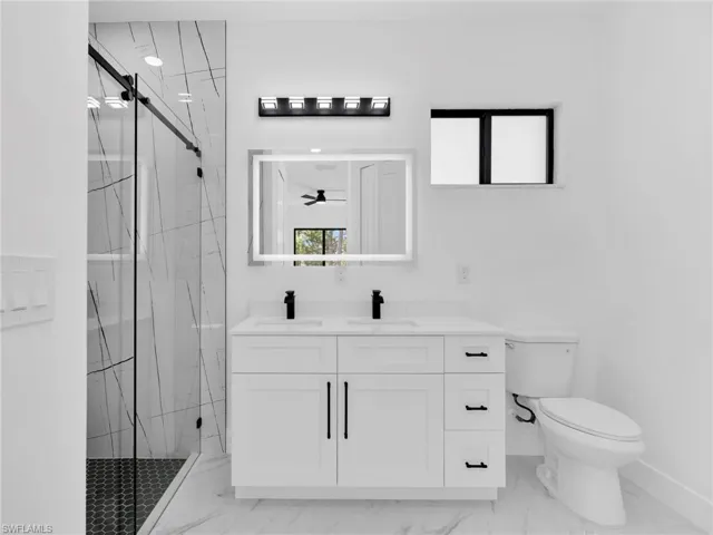 Bathroom with a marble finish shower, vanity, and light marble finish floors