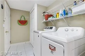 Washroom with light tile patterned flooring and washer and dryer