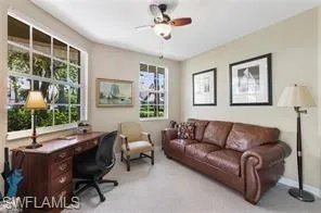 Carpeted home office featuring a ceiling fan and baseboards