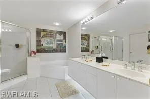 Full bathroom featuring a bath, a shower stall, double vanity, and light tile patterned floors