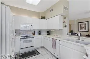 Kitchen featuring light countertops, white appliances, white cabinetry, and light tile patterned floors