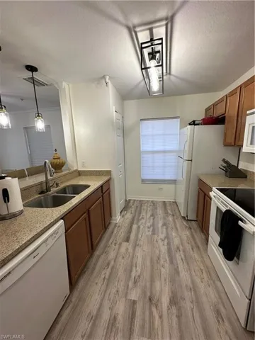 Kitchen featuring white range, brown cabinetry, dishwasher, a textured ceiling, and decorative light fixtures