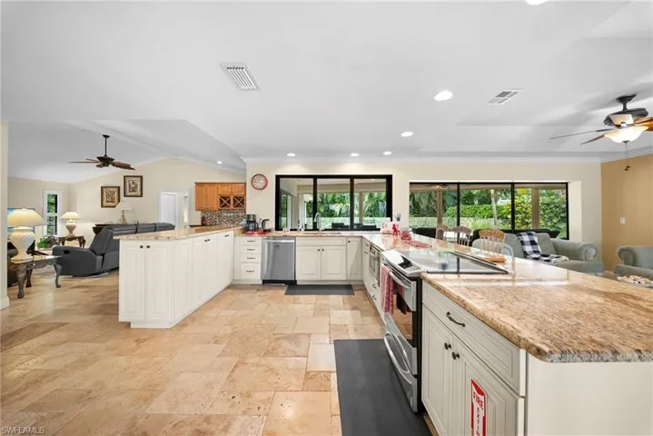 Spacious kitchen featuring an extended island, integrated stovetop, light cabinetry, stone countertops, and tile flooring