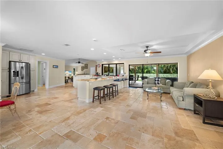 Expansive living area with large-format stone tile flooring, crown molding, and recessed lighting