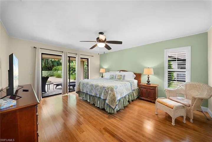 Wood-finish flooring throughout, ceiling fan with integrated lighting, sliding glass door patio access, and a window with plantation shutters