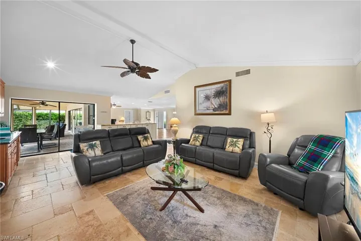 Varnished wood-finish ceiling fan, vaulted ceiling, tile flooring, sliding glass doors, and a built-in counter with cabinetry