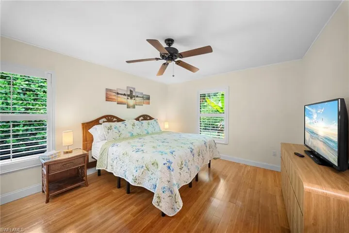 Wood-finish flooring, ceiling fan, and two windows with horizontal blinds