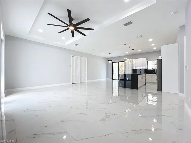 Unfurnished living room with crown molding, a tray ceiling, and ceiling fan