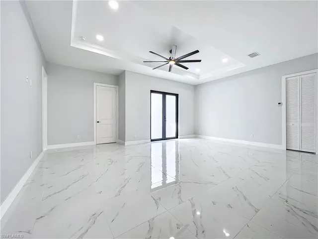 Empty room with french doors, ceiling fan, and a tray ceiling