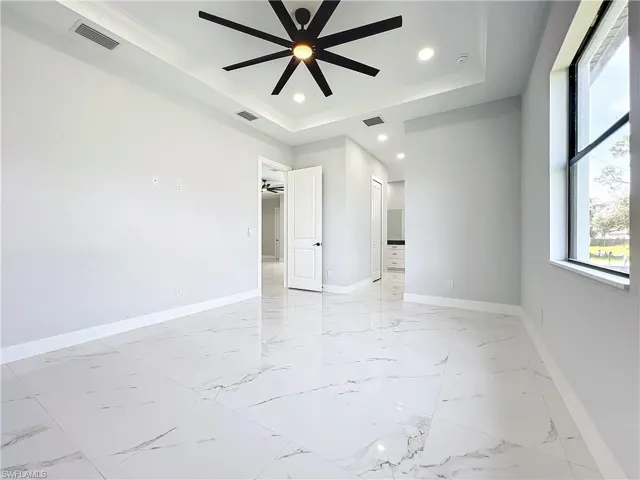 Unfurnished room with ornamental molding, ceiling fan, and a raised ceiling