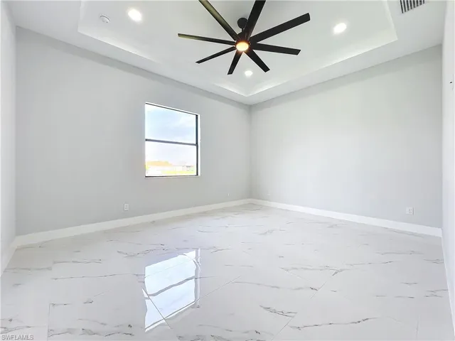 Unfurnished room featuring ceiling fan and a raised ceiling