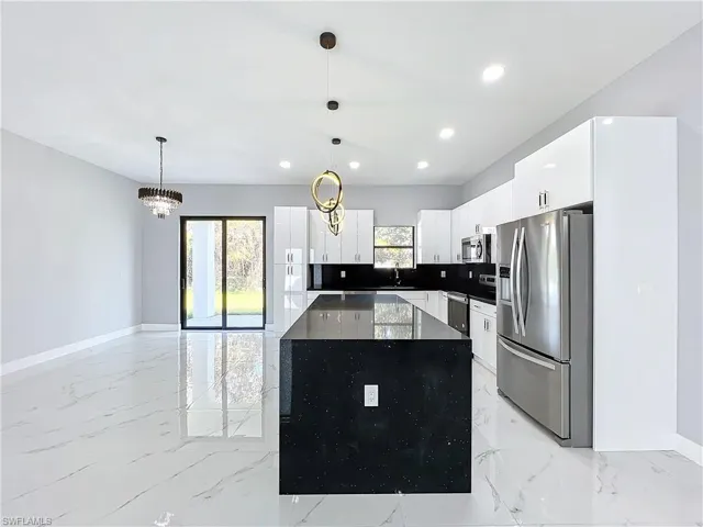 Kitchen featuring sink, white cabinets, a notable chandelier, decorative light fixtures, and appliances with stainless steel finishes