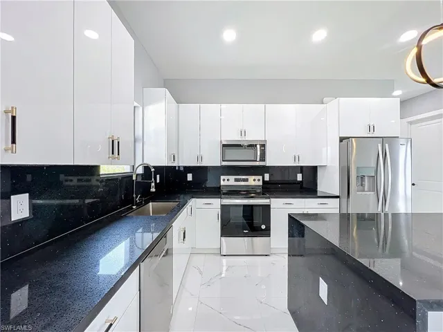 Kitchen featuring white cabinetry, stainless steel appliances, and sink