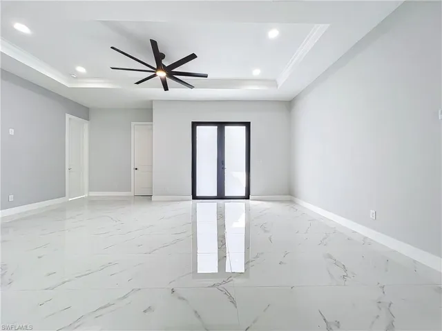 Unfurnished room featuring crown molding, a tray ceiling, french doors, and ceiling fan