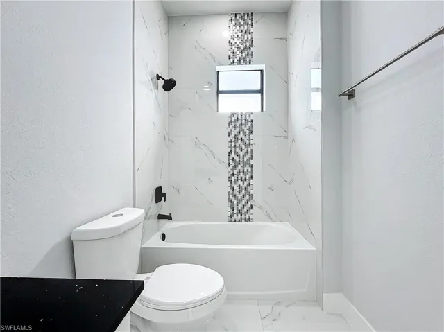 Full bathroom with vanity, toilet, and tiled shower / bath combo