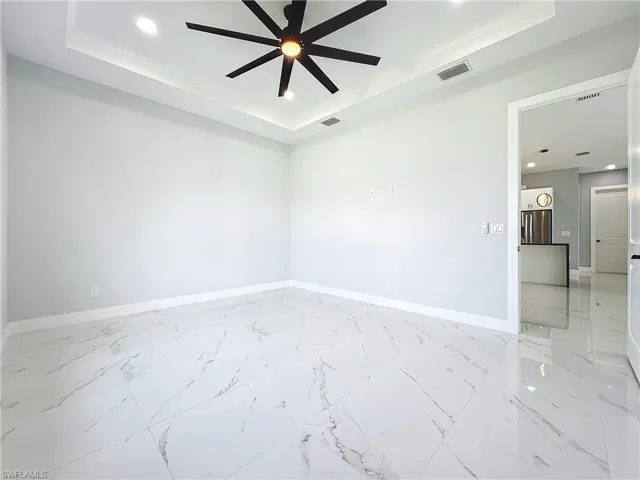 Empty room featuring ornamental molding, ceiling fan, and a raised ceiling