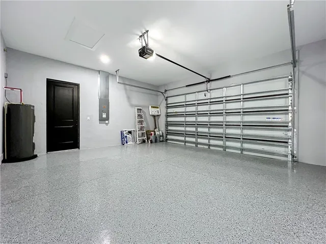 Garage with a garage door opener, electric water heater, and electric panel