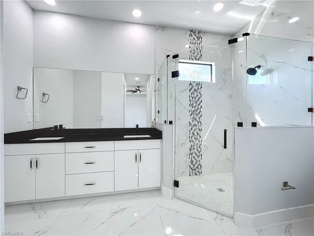 Bathroom featuring vanity, ceiling fan, and an enclosed shower