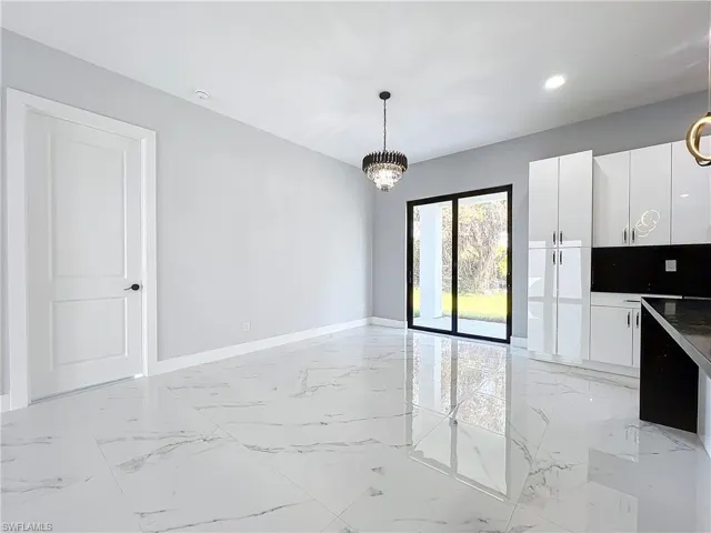 Kitchen with a notable chandelier, white cabinets, and hanging light fixtures