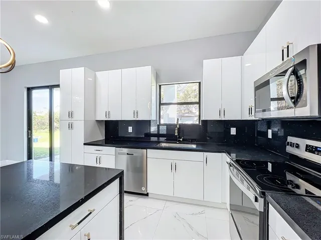 Kitchen featuring a wealth of natural light, sink, white cabinets, and stainless steel appliances
