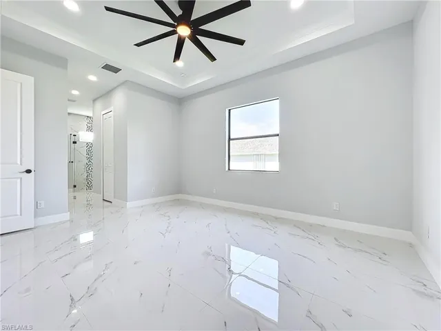 Spare room featuring a tray ceiling and ceiling fan