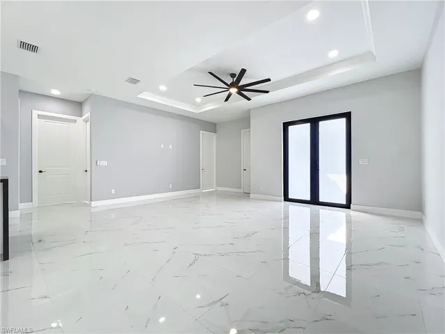 Empty room featuring ceiling fan and a raised ceiling