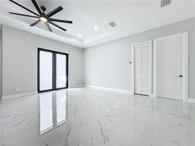 Unfurnished room featuring french doors, ceiling fan, and a tray ceiling