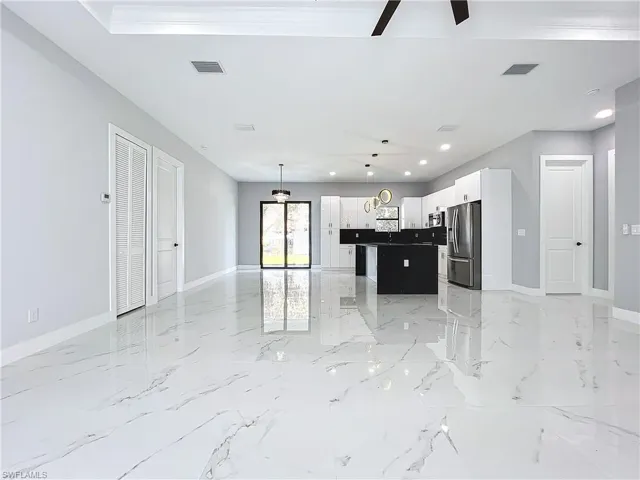 Kitchen featuring stainless steel refrigerator with ice dispenser, a center island, pendant lighting, an inviting chandelier, and white cabinets
