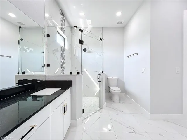 Bathroom with a shower with door, toilet, and vanity