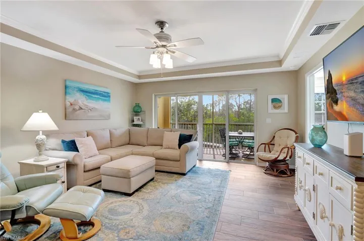 Living room featuring crown molding, a healthy amount of sunlight, and a tray ceiling