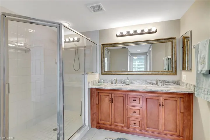 Bathroom with walk in shower, vanity, and tile patterned flooring