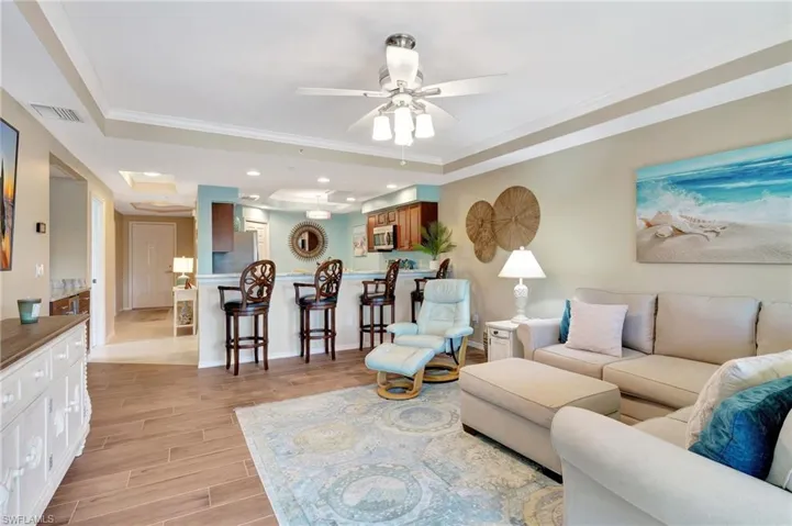 Living room with crown molding, ceiling fan, and a tray ceiling