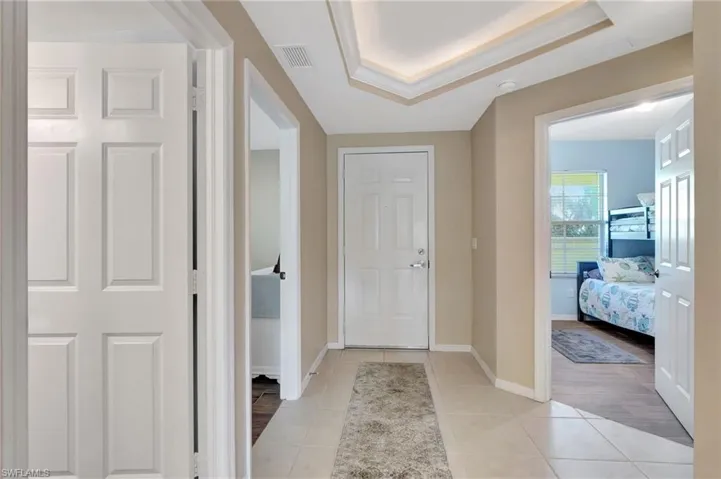 Tiled entrance foyer featuring crown molding and a tray ceiling