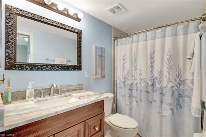 Bathroom with vanity, toilet, and a shower with shower curtain