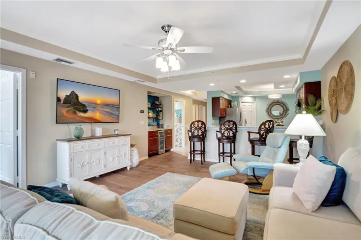 Living room featuring wine cooler, crown molding, a raised ceiling, ceiling fan,