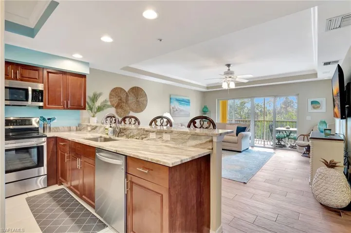 Kitchen with a raised ceiling, appliances with stainless steel finishes, sink, and kitchen peninsula