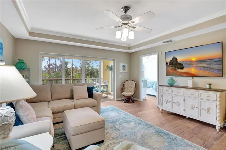 Living room featuring crown molding, ceiling fan, a tray ceiling, and light hardwood looking tile