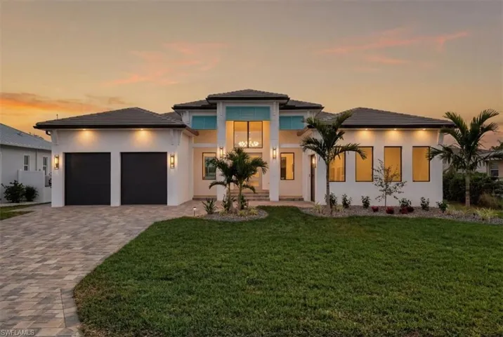 Prairie-style house with a front lawn, decorative driveway, an attached garage, and stucco siding