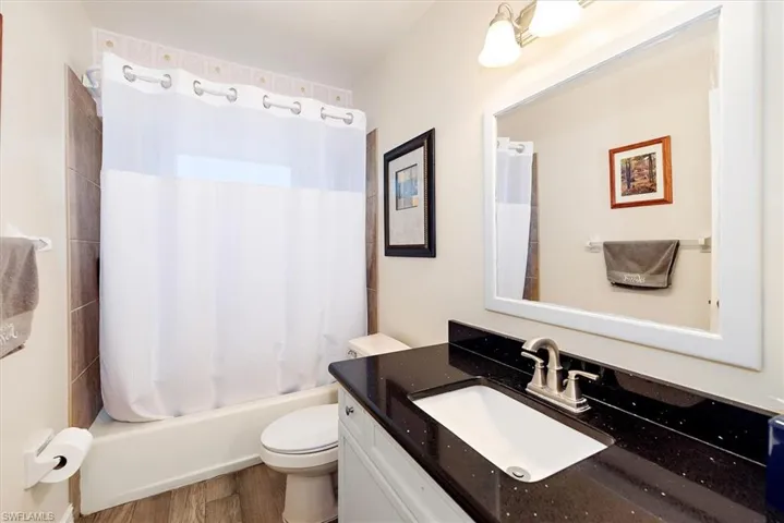 Full bathroom featuring shower / tub combo, vanity, and dark wood-style floors