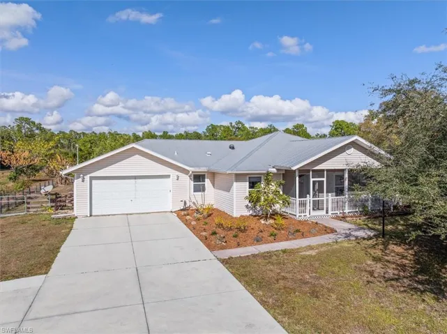 Ranch-style home featuring a sunroom, driveway, a garage, and a front yard