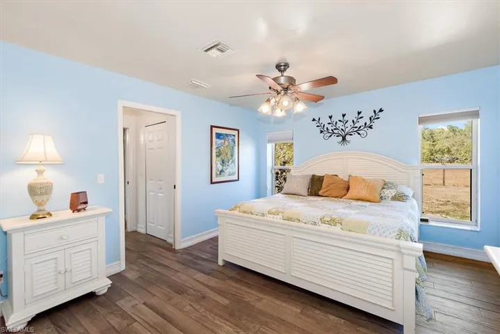Bedroom featuring dark wood-type flooring, multiple windows, and ceiling fan