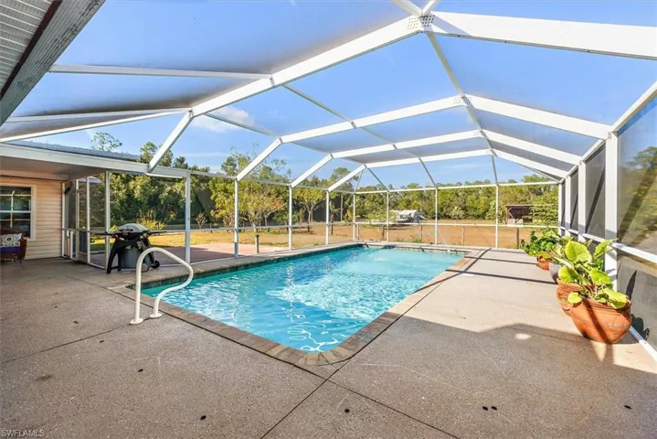 Swimming pool featuring a patio area, a sunroom, glass enclosure, and area for grilling