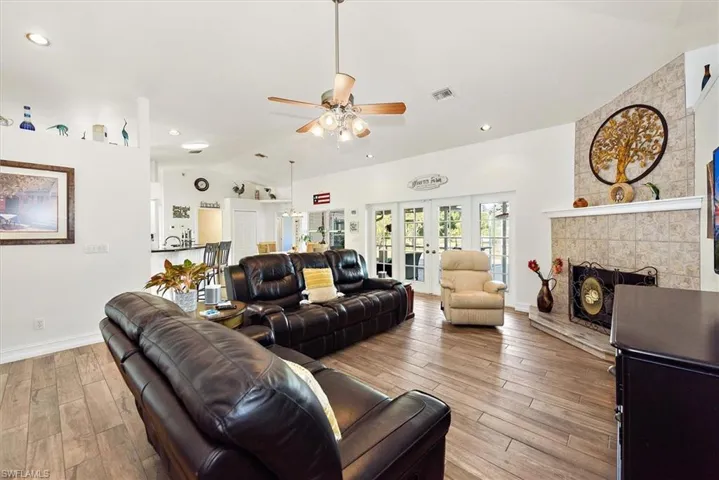 Living room featuring wood tiled floors, french doors, lofted ceiling, recessed lighting, and ceiling fan