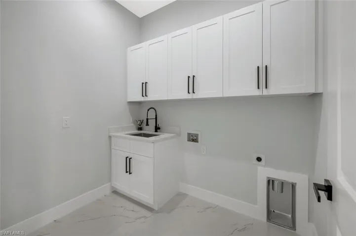 Laundry room with cabinet space, hookup for a washing machine, light marble finish flooring, and electric dryer hookup