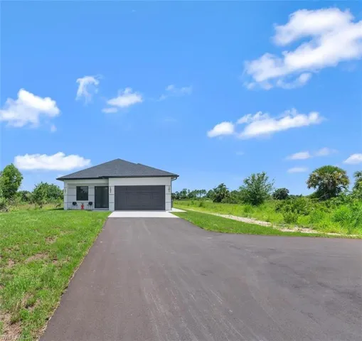 View of front of property featuring driveway, an attached garage, and a front lawn