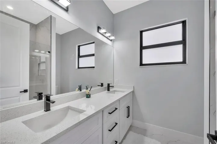 Bathroom featuring double vanity, a stall shower, and light marble finish floors