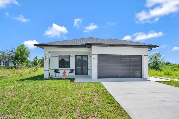 View of front of property with a garage, concrete driveway, a front yard, roof with shingles, and a porch