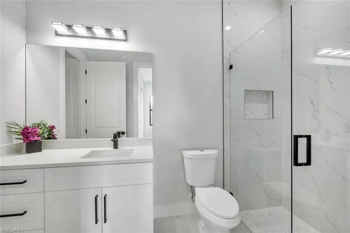 Full bath featuring vanity and a marble finish shower